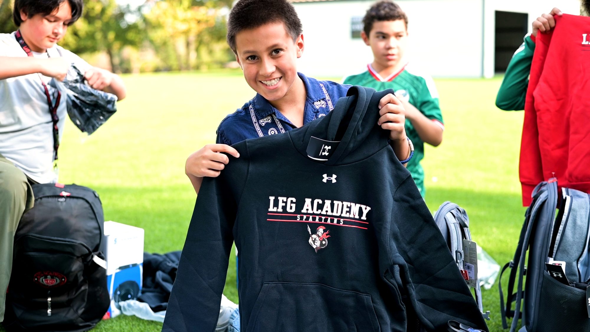 An LFG Academy student holding up a team hoodie on the field
