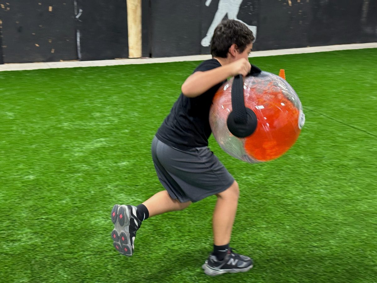 A student sprinting with a weighted ball during performance training